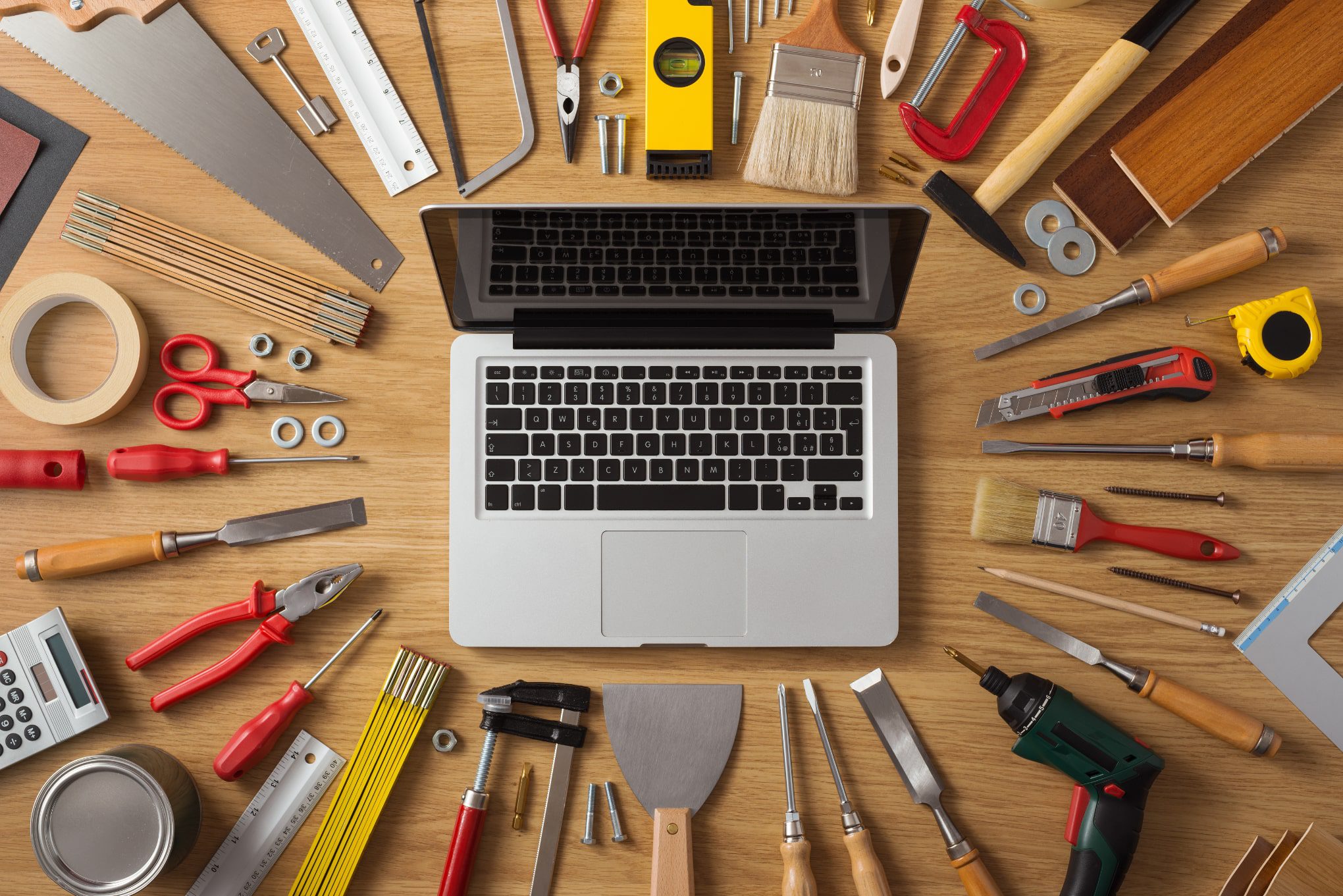 A computer surrounded by tools and items representing what a website is built out of.